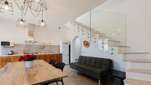 Een moderne keuken met een zithoek, een bank en een trap met glazen leuning.
