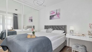 Un dormitori modern amb un llit, una taula de nit i un escriptori amb una cadira.