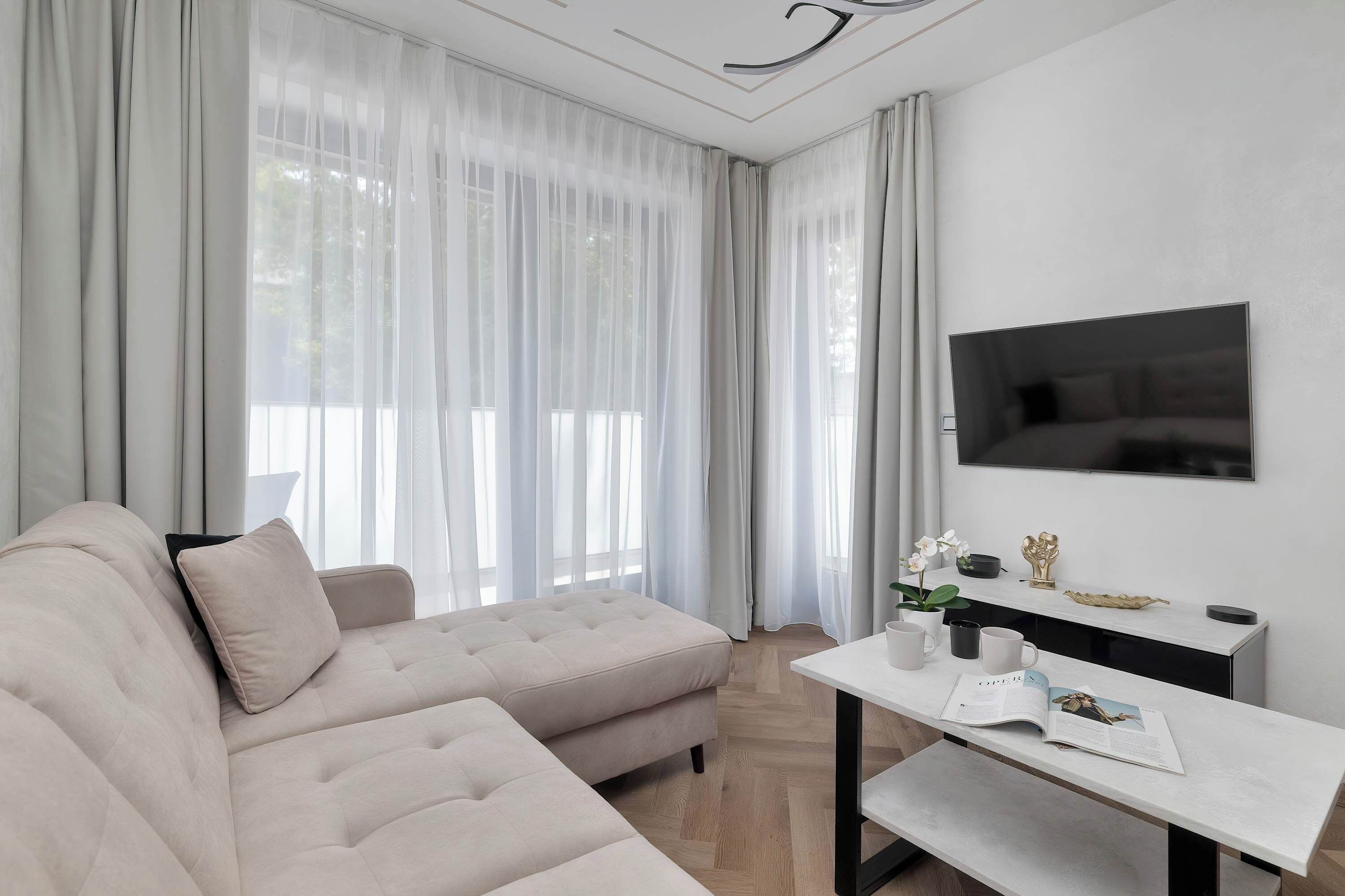 A close-up perspective of the living room highlights the plush texture of the beige L-shaped sofa. The minimalist decor creates an atmosphere of calm and relaxation.