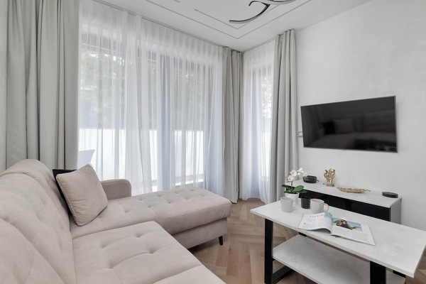 A close-up perspective of the living room highlights the plush texture of the beige L-shaped sofa. The minimalist decor creates an atmosphere of calm and relaxation.