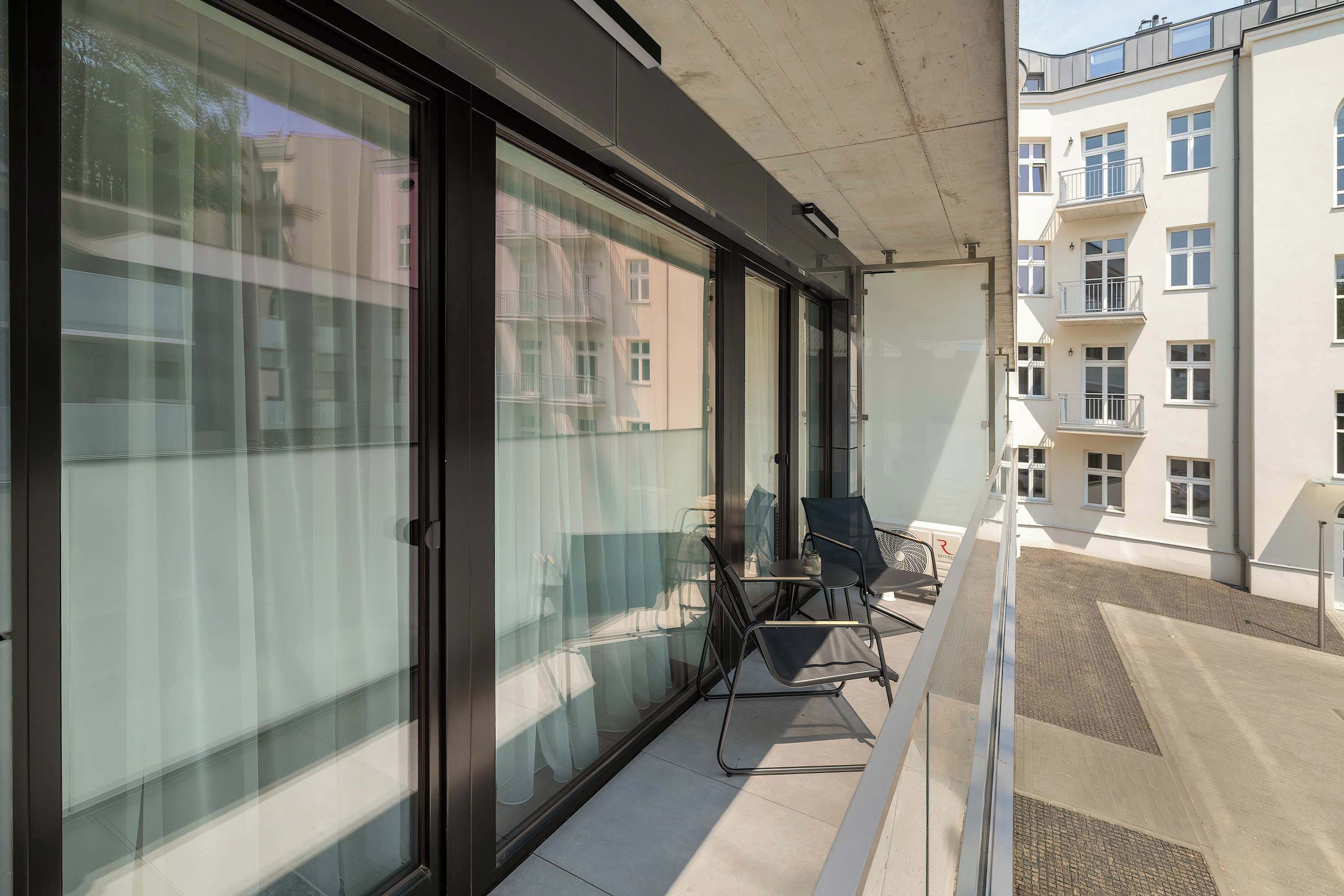 Ein Balkon mit Glastüren, einem Stuhl und einem kleinen Tisch.