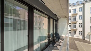 Un balcó amb portes de vidre, una cadira i una taula petita.