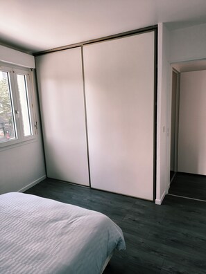 Une chambre à coucher avec un lit, une armoire et une fenêtre.