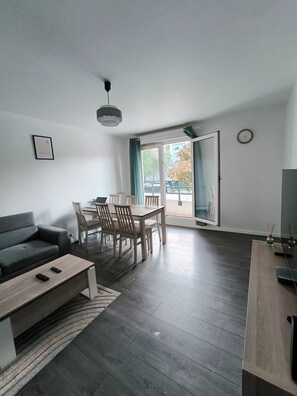 Un salon moderne comprenant un canapé, une table à manger, des chaises et un téléviseur.