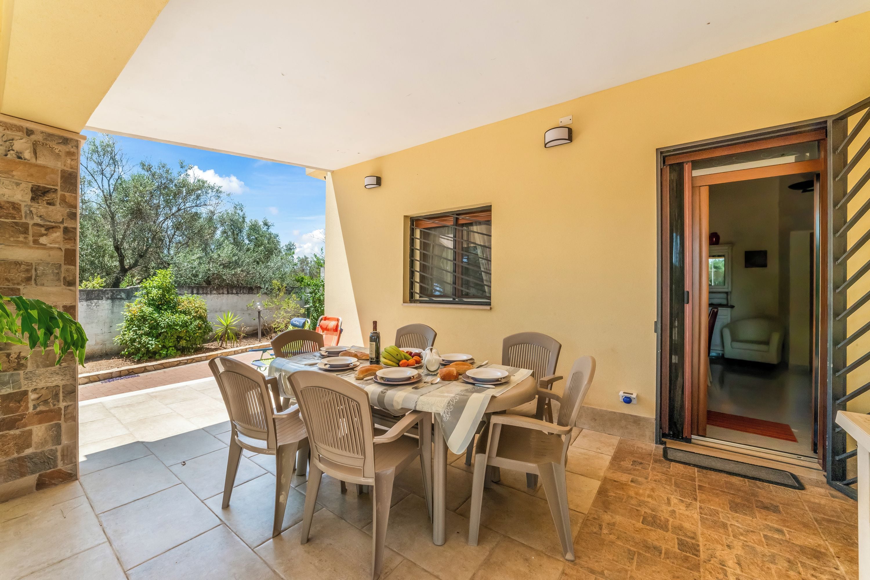 A dining area with a table set for four, chairs, a window, and a door leading to another room.