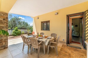 A dining area with a table set for four, chairs, a window, and a door leading to another room. - Villa Armonia Cordis (Sava)