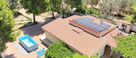 Propiedad residencial con piscina, paneles solares y techo de tejas rojas.