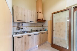 Una cocina con armarios de madera, un lavamanos de acero inoxidable y una estufa a gas.