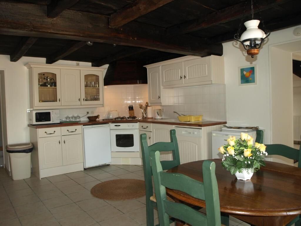 A kitchen with white cabinets, a dining table with chairs, and a hanging light fixture.
