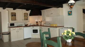 A kitchen with white cabinets, a dining table with chairs, and a hanging light fixture.