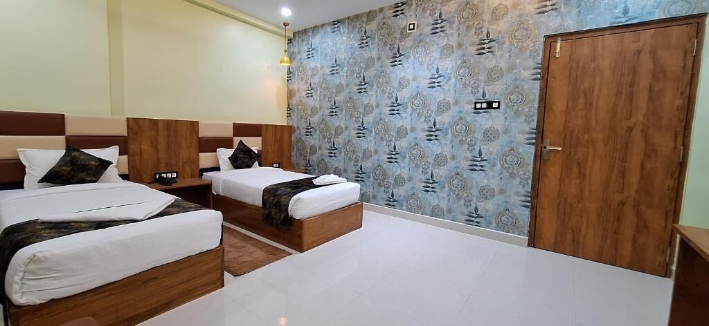 A hotel room with three beds, a wooden wardrobe, and a patterned wall.