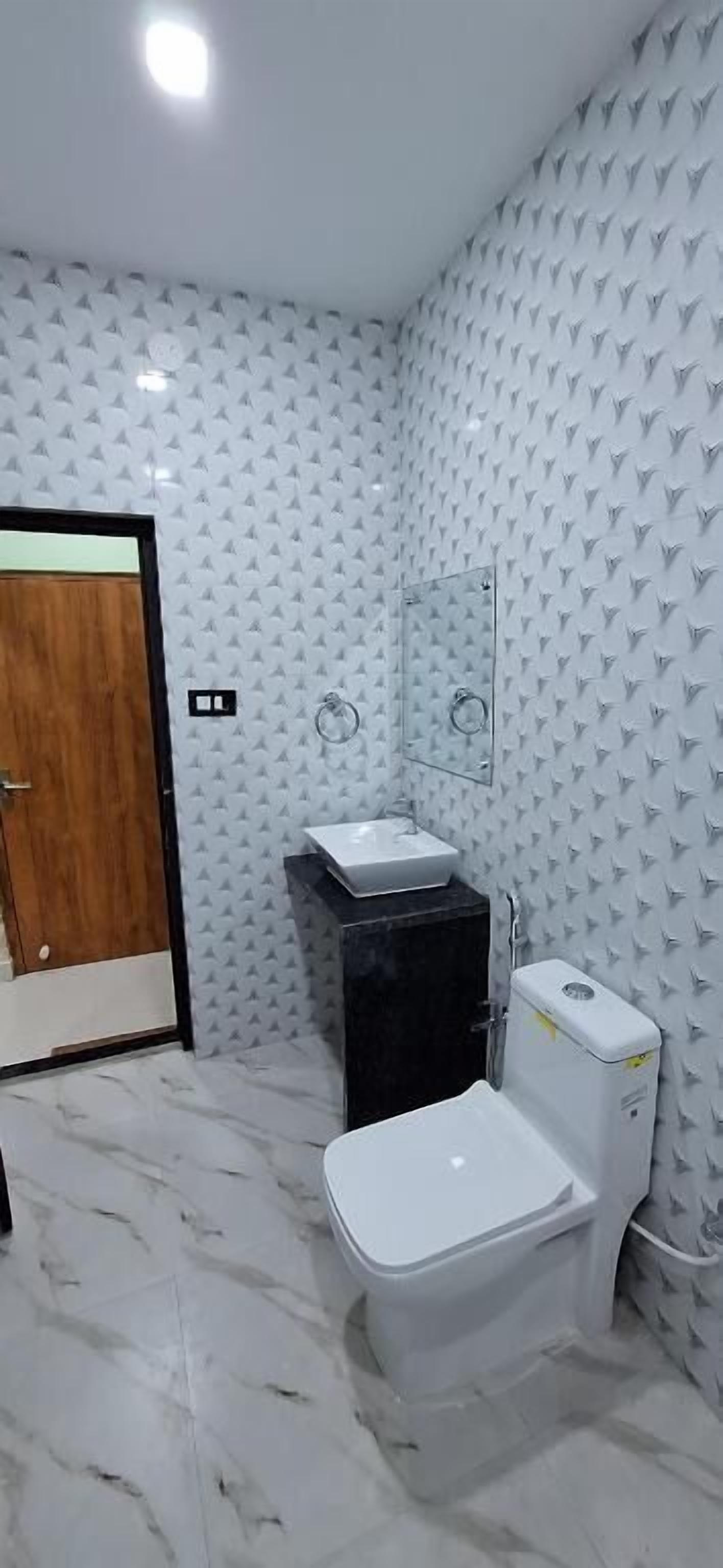 A bathroom with a toilet, sink, and mirror.