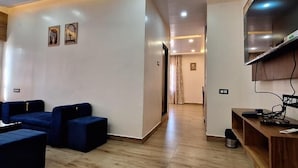 Una sala de estar moderna con televisión, zona de estar y un pasillo que lleva a otra habitación.