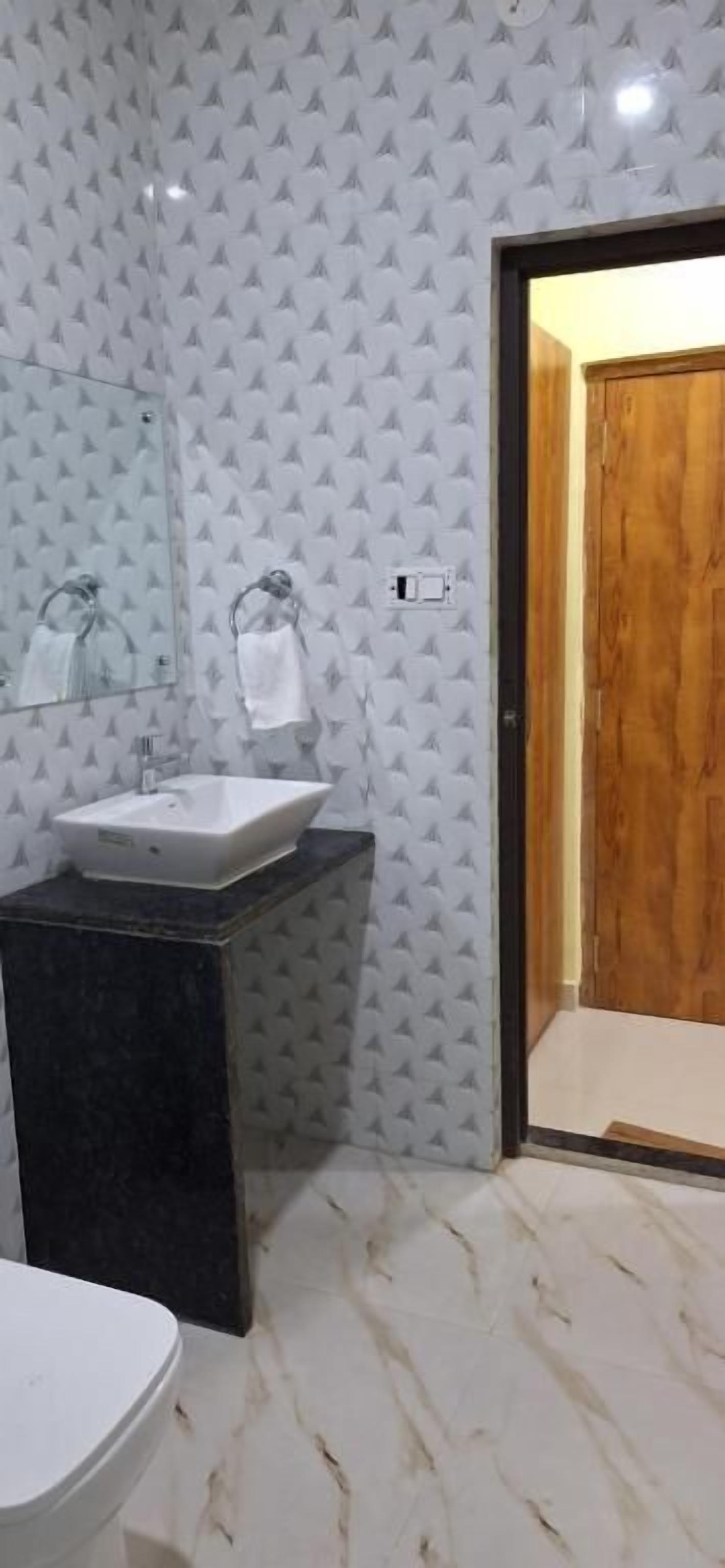 A bathroom with a white toilet, a sink with a mirror, and a wooden door.