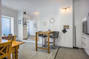 A modern kitchen with a wooden table, bar stools, and a built-in oven.