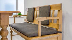 A wooden bench with a cushioned seat and backrest, positioned against a wall.