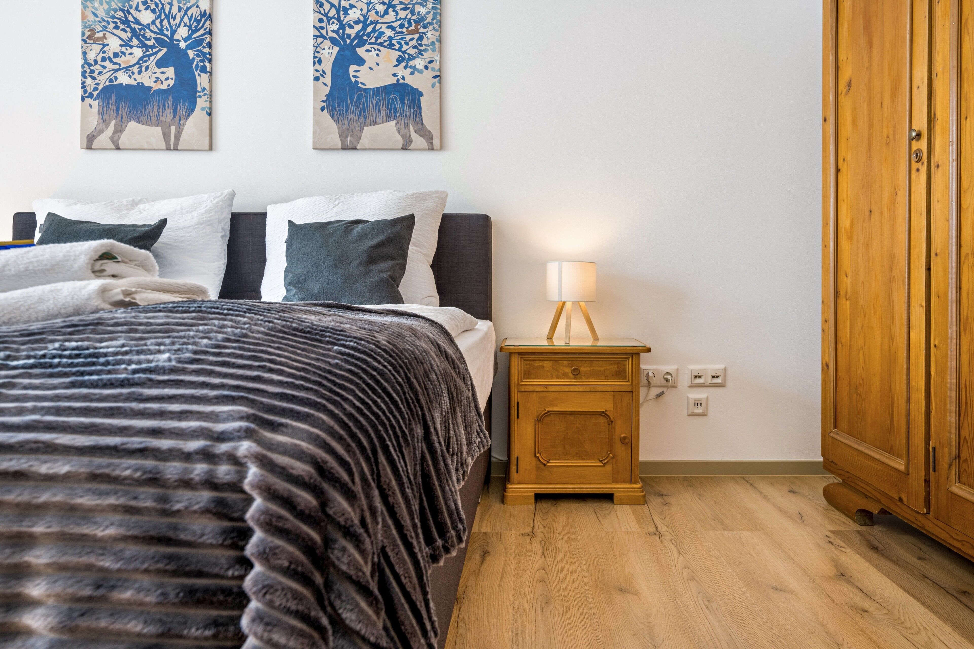 Una camera da letto con un letto, cuscini, un comodino con una lampada e un armadio.