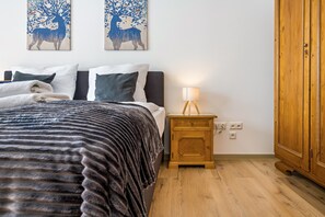Un dormitorio con cama, almohadas, una mesita de noche con lámpara y un armario.