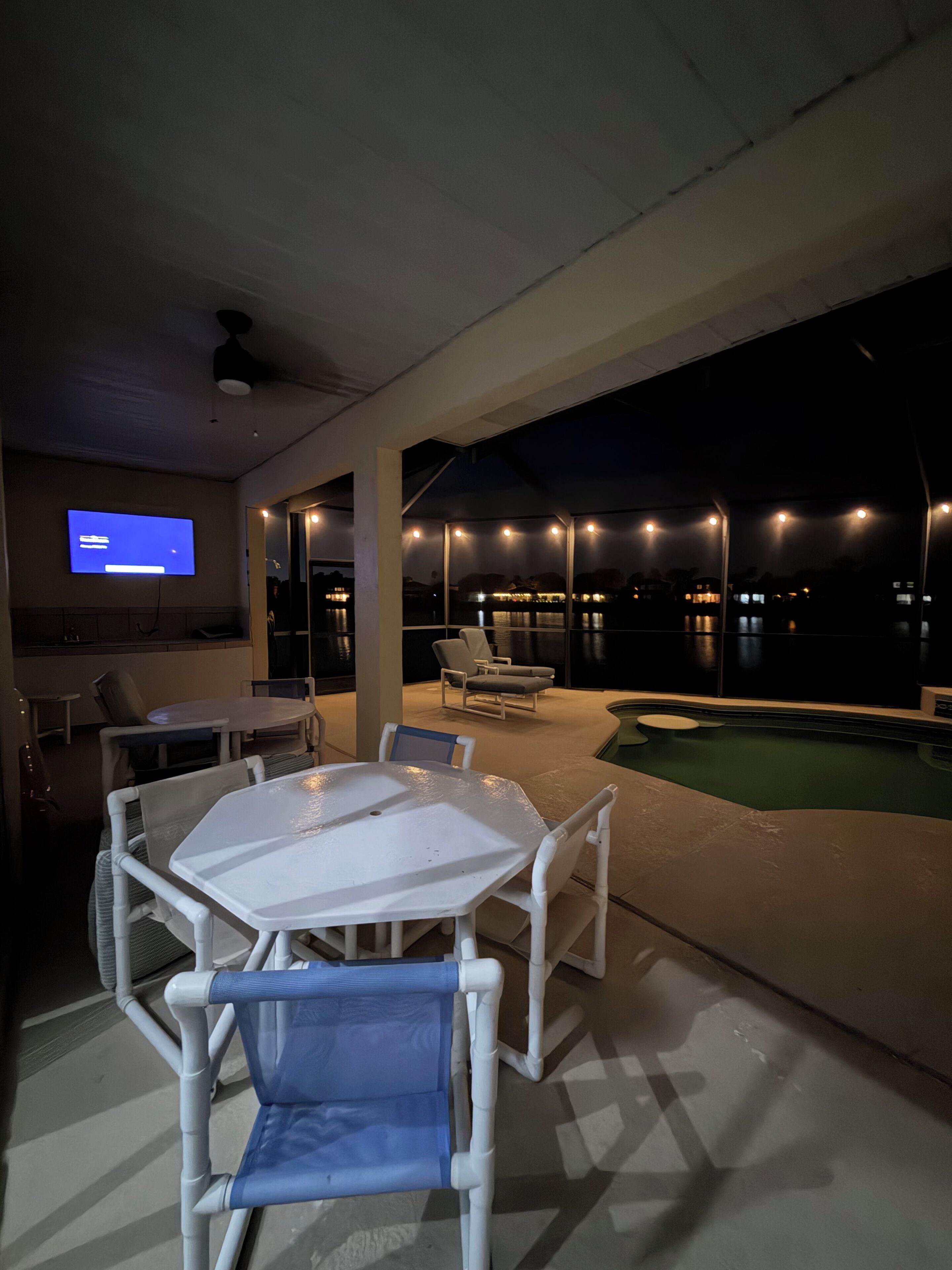 Eine Außenpatio mit Pool, Sitzgelegenheiten und einem Fernseher.