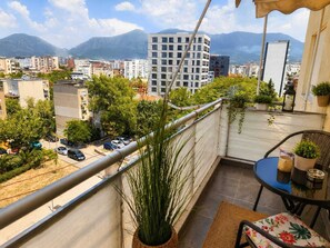 A balcony with a view of a cityscape, including a tall building and mountains in the background. - Modern Central Tirana Apartment with Free Parking & Fast WiFi (Tiranë)