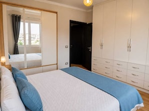 Un dormitorio con una cama, un armario y un espejo.
