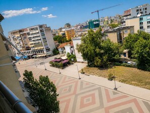 A cityscape with buildings, a construction crane, and a patterned pavement. - Modern Central Tirana Apartment with Free Parking & Fast WiFi (Tiranë)
