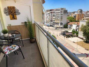 Un balcón con una mesa y sillas, una planta en maceta y una obra de arte colgada en la pared.