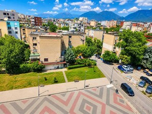 A residential area with multi-story buildings, a paved road, and a grassy area. - Modern Central Tirana Apartment with Free Parking & Fast WiFi (Tiranë)