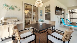 A kitchen with a grill, dining table, chairs, and a chandelier. - 4359-Rhyme (Kissimmee)