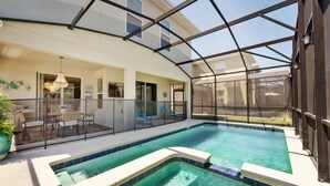 A covered outdoor swimming pool with a patio area, seating, and a view of the adjacent building. - 4359-Rhyme (Kissimmee)