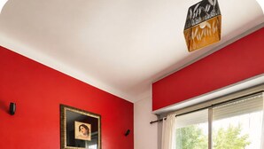 Een woonkamer met een rode bank, een grijze bank, een houten salontafel en een schilderij aan de muur.