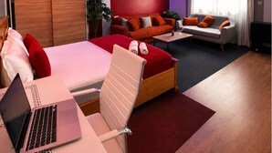 Een moderne slaapkamer met een bed, een bureau met een laptop, een bank en een salontafel.