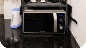 Een kleine keuken met een magnetron, koffiezetapparaat en waterkoker op een aanrecht.