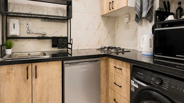 Een kleine keuken met een vaatwasser, wasmachine en magnetron.