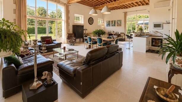 Amplia sala de estar con techo alto, ventanas grandes, comedor y cocina.