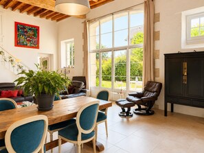 A spacious room with a wooden dining table, blue upholstered chairs, a leather sofa, and a large window offering a view of greenery. - A place to recharge your batteries at the foot of the Pyrenees (Meillon)