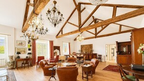 Amplia habitación con vigas de madera, muebles de cuero y candelabros.