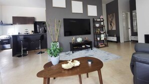 Een moderne woonkamer met een televisie, een bijzettafeltje en een plant.