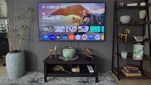 Een flatscreen televisie bevestigd aan een muur, met een afstandsbediening op een voet eronder.