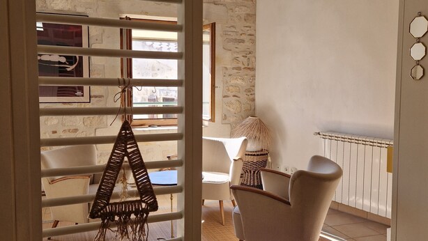 A room with a stone wall, a chair, a table, and a hanging macrame decoration. - Dupleix and an open-air terrace (Saint-Gilles)