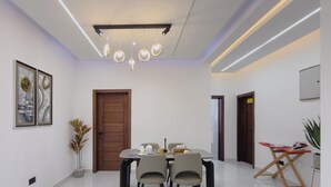 Un espace repas moderne avec une porte en bois, une table à manger avec des chaises et un luminaire suspendu au plafond.