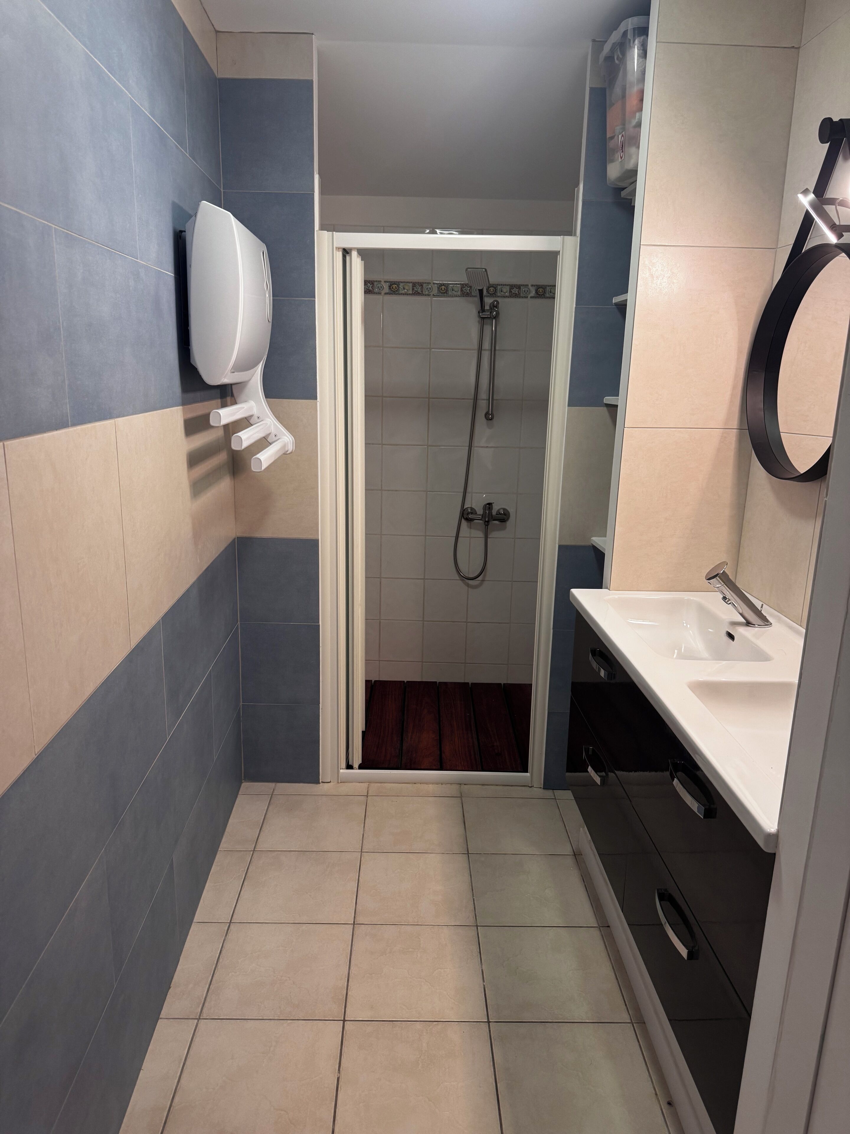 Une salle de bain équipée d’une douche, d’un lavabo et d’un sèche-mains.