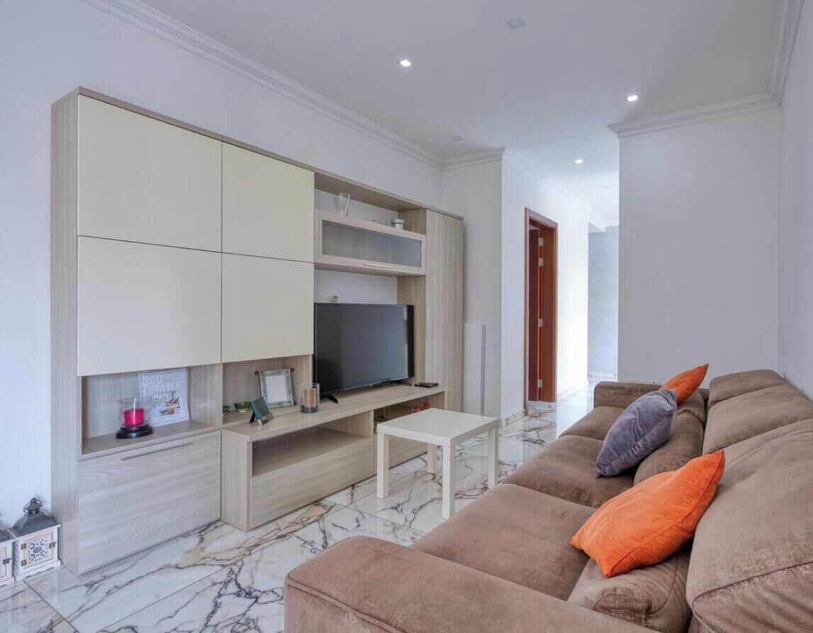 Una sala de estar con sofá, televisor y una mesita.