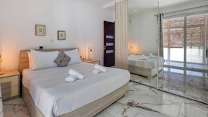 Hotelkamer met een groot bed, nachtkastje, spiegel en een schuifdeur naar een balkon.