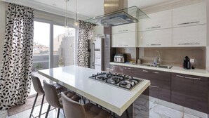 Een moderne keuken met een centraal eiland, roestvrijstalen apparatuur en donkere kastjes.