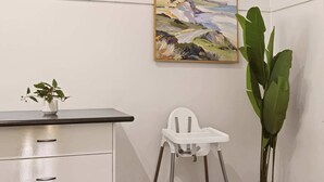 A room with a desk, a white chair, a painting, and a potted plant. - Modern Family house with BBQ (Dubbo)
