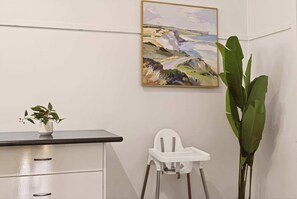 Una habitación con un escritorio, una silla blanca, un cuadro y una planta en maceta.