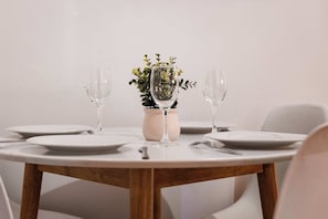 A round dining table with white plates, two wine glasses, and a vase with green foliage. - Modern Family house with BBQ (Dubbo)