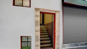 Een gebouwde ingang met een houten deur, een trap die naar binnen leidt, en een gesloten garagepoort.