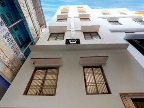 A hotel with a sign indicating 'HOTEL' and 'Hotel Services.' It features a modern design with multiple windows and a flat roof. - Deluxe Hotel O Dashashwamedh Ghat (Varanasi)